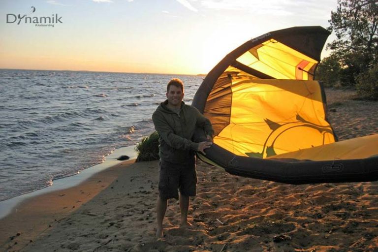 Chad the owner of Dynamik Kiteboarding holding a kiteboarding kite on a beach