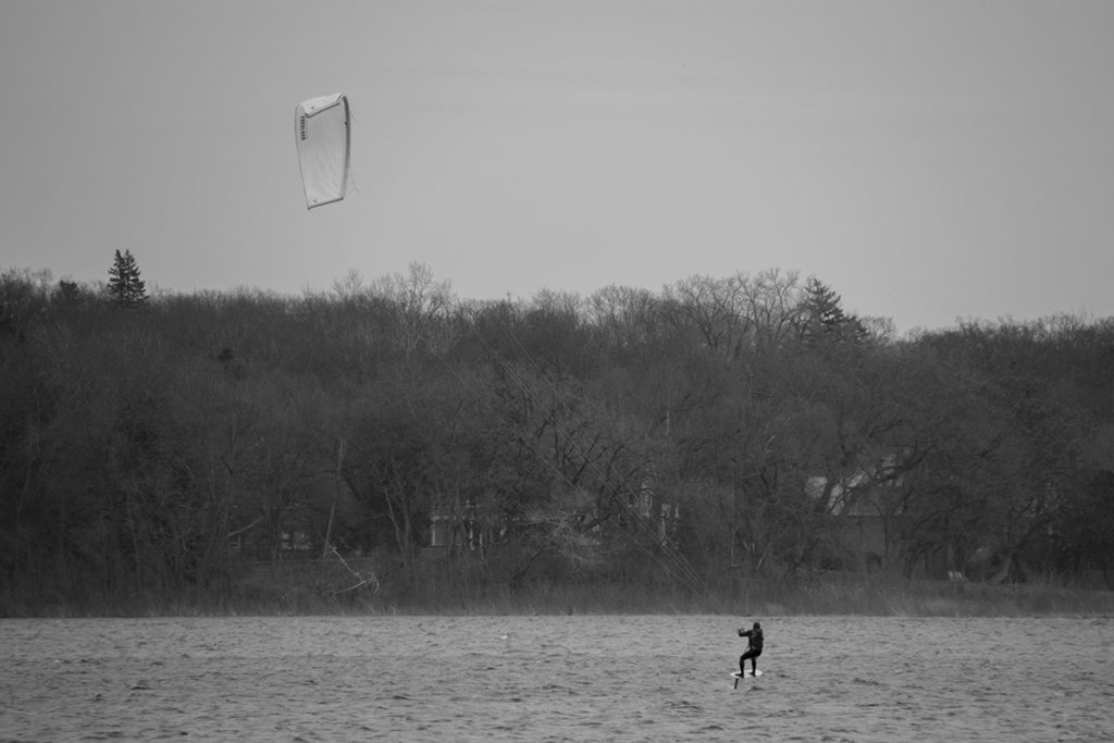 A kiteboarder on a foil board lifts off the water.