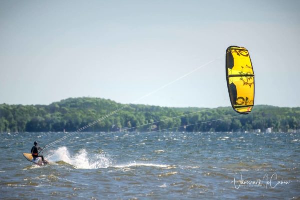 Kitesurfer riding in on a sunny day with a yellow kite