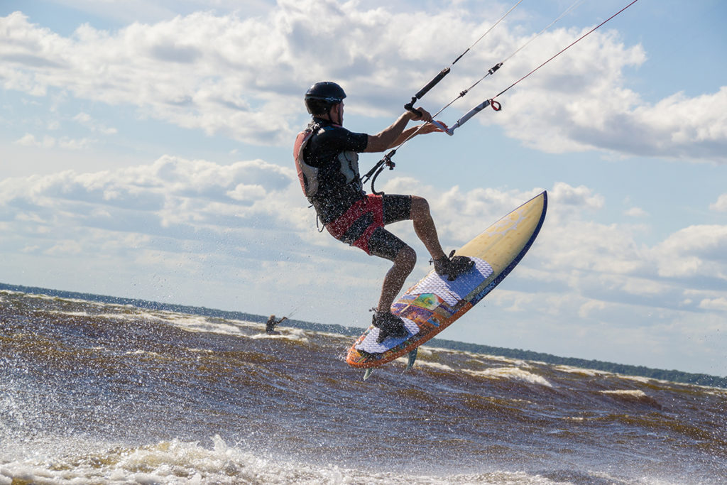 Kitesurfer popping off a wave with water spraying around