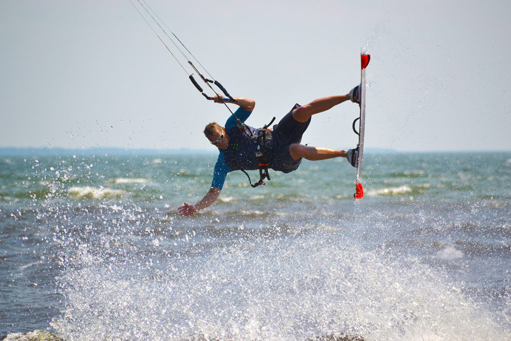 A kiteboarder jumps above the water on a sunny day.