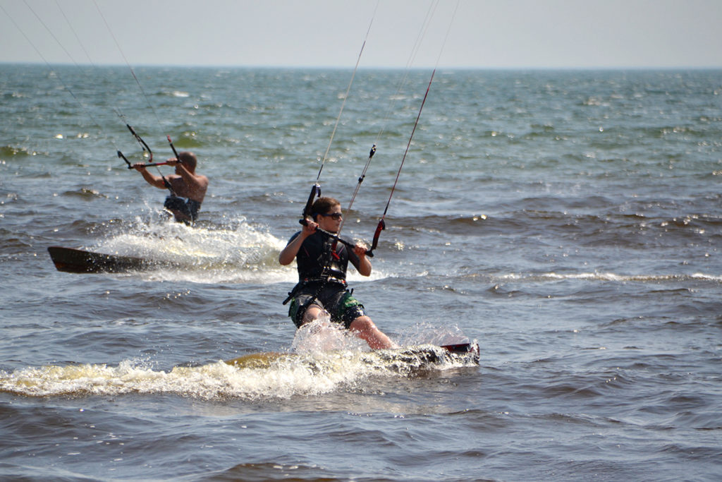 Two kiteboarders pass by each other on a sunny day